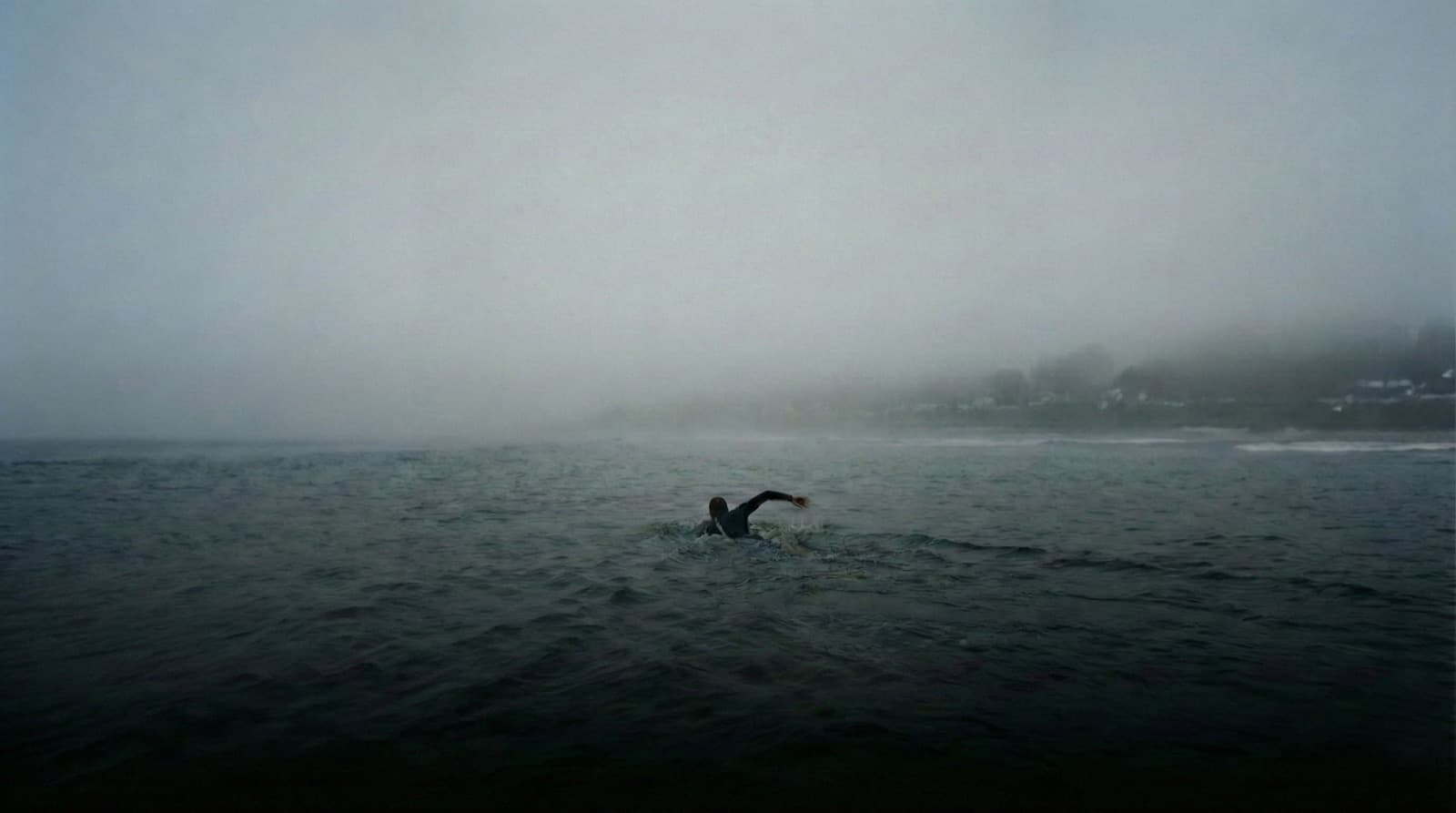 Пловец в тумане плывёт к едва видимому берегу